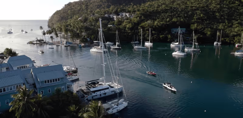 Sailboats anchored in a tropical bay surrounded by lush green hillside